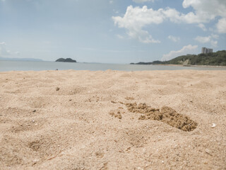 low angle photo of beach showing sand, sea and island in background