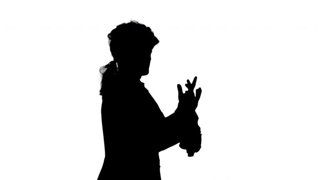 Silhouette Man dressed as courtier talking expressively and waiving his hands while walking and looking at camera.