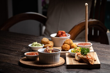 Spanish food ingredients on dark old wooden background, appetizers knowns as tapas with seafood, fish, meet, red sauces, greens, vegetables. Healthy food. Vegan, vegetarian on the white plate.