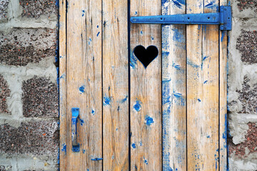        A silhouette of a heart carved in a plank toilet door in the countryside.