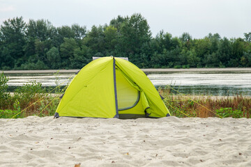       Yellow tent on the sandy bank of the river.