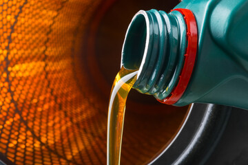 against the background of a burning filter, engine oil is pouring from the neck of the bottle into...