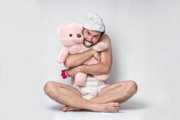 Infant adult man with pacifier in diaper holding pink teddy bear