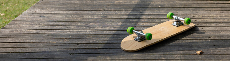 inverted skateboard with green wheels on wooden ramp, panorama © Christian Ca