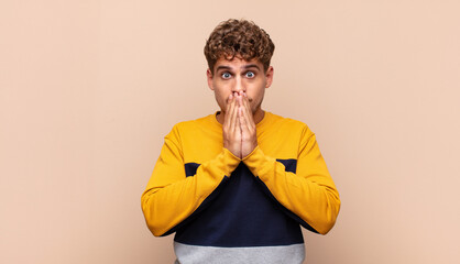 young man happy and excited, surprised and amazed covering mouth with hands, giggling with a cute...