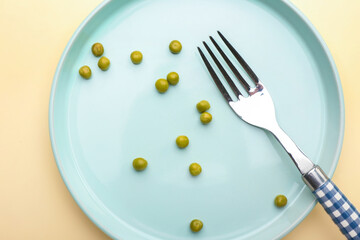 Plate with peas and fork on color background. Concept of anorexia