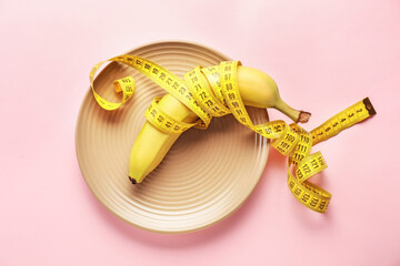 Plate with measuring tape and banana on color background. Concept of anorexia