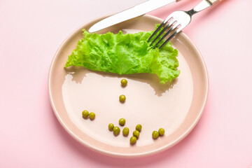 Plate with vegetables and cutlery on color background. Concept of anorexia