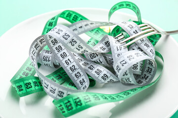 Plate with measuring tapes and fork, closeup. Concept of anorexia
