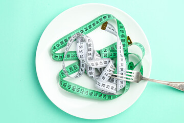 Plate with measuring tapes and fork on color background. Concept of anorexia