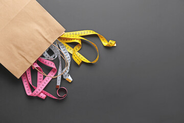 Bag with measuring tapes on dark background. Concept of anorexia