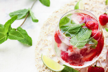 Glass of fresh strawberry mojito on light background