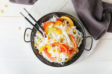 Frying pan with tasty rice noodles and vegetables on table