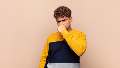 young man feeling disgusted, holding nose to avoid smelling a foul and unpleasant stench