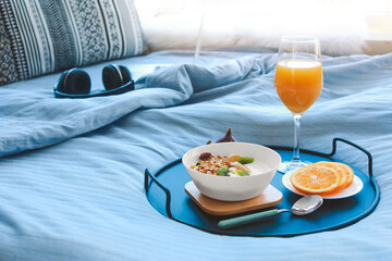 Tray with tasty breakfast on bed