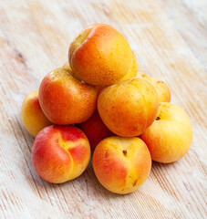Naklejka na ściany i meble Heap of ripe reddish apricots on wooden table. Concept of health benefits of fruits.