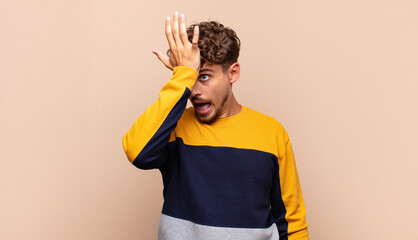 young man raising palm to forehead thinking oops, after making a stupid mistake or remembering,...