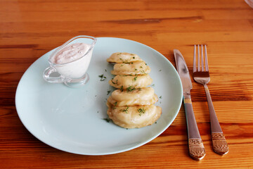 Vareniki on a plate with creamy sauce. Fork and knife.