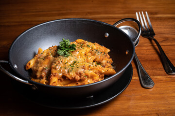 Pasta penne with spicy tomato sauce, parmesan and parsley. Pasta Chifferi Rigati. Tomato, olive oil, spices, herbs, cheese, tomato sauce on a wooden table.