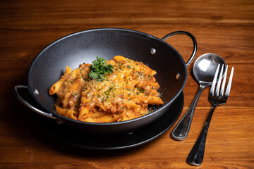 Pasta penne with spicy tomato sauce, parmesan cheese white wine sauce and parsley. Pasta Chifferi Rigati. Tomato, olive oil, spices, herbs, cheese, tomato sauce on a brown wooden table. Yellow, brown