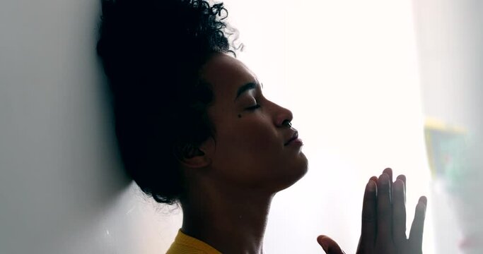Young black woman praying looking for hope and faith, putting hands in chest