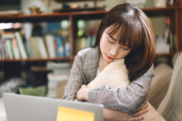 Asian teenager woman closed eye and take a sitting nap with laptop work at home