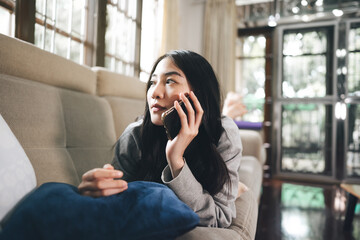 Young adult asian woman using mobile phone for tele medicine at home