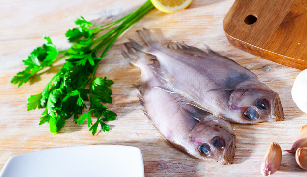 Two raw Atlantic megrims on wooden table with condiments. Seafood delicacy