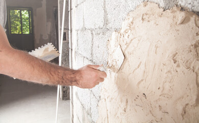 Man is applying putty on a wall. Renovating house