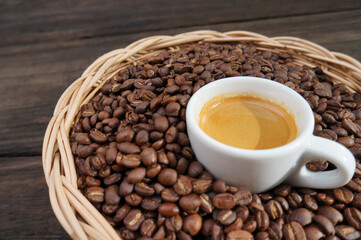 Espresso coffee in a white mug and coffee beans on a wooden table.