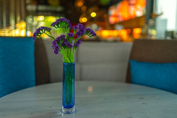 Beautiful purple flower bouquet in a glass vase on the reception table.