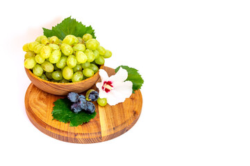 Bunches of grapes and hibiscus flower on a wooden board. White background.