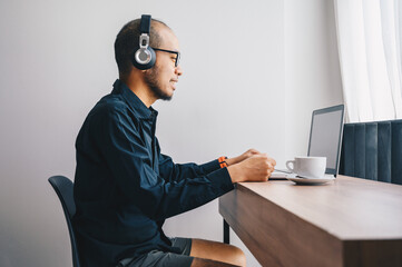 Young Asian businessman wearing shirt and casual shorts while online conference from home. Conceptual of working from home in covid-19 pandemic.