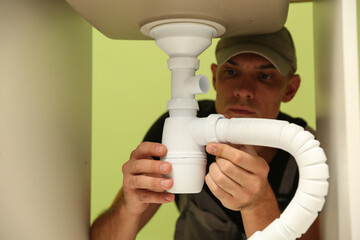 plumber installs a siphon pipe on the kitchen sink. refurbishment in the apartment. elimination of leakage in the sink. 