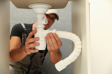 plumber installs a siphon pipe on the kitchen sink. refurbishment in the apartment. elimination of leakage in the sink. 