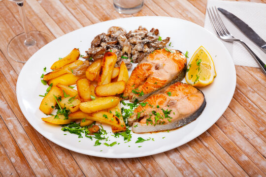 Image of deliciously steak of fried salmon with potatoes and mushrooms on plate