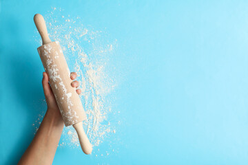 Female hand hold rolling pin on blue background
