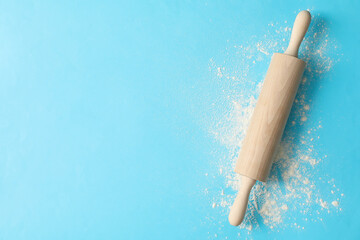 Rolling pin and flour on blue background