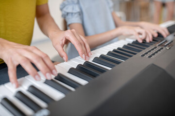 Obraz premium Close up picture of two people playing piano together