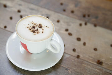 Cup of cappuccino and beans on a wooden table