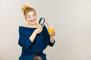 Woman holding magnifying glass investigating juice