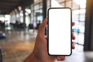 Mockup image of a man holding black mobile phone with blank white screen in cafe