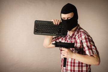 Man in balaclava holding keyboard and gun
