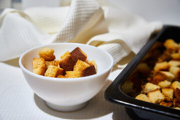 Square toasted pieces of homemade delicious rusk, hardtack, Dryasdust, zwieback on a white plate and baking sheet.