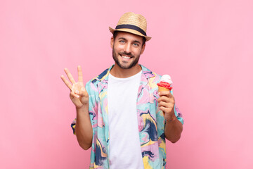 young man smiling and looking friendly, showing number three or third with hand forward, counting...