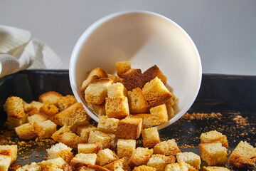 Square toasted pieces of homemade delicious rusk, hardtack, Dryasdust, zwieback on a white plate and baking sheet.