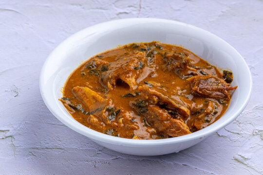 Upclose photo of Ogbono Soup with stockfish in a white ceramic plate on an embossed background