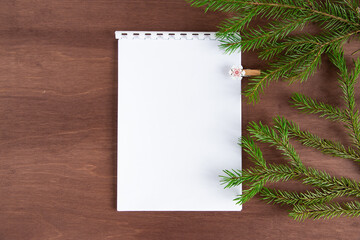 Blank paper and fir branches on a dark wooden background. Christmas concept. Flat lay, top view.