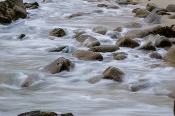 Long exposure Pacific seascape waves on the rocky stoney shore. Slow shutter speed used to see the movement (Soft focus shot)