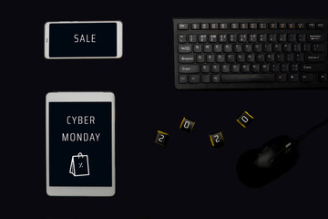 Cyber Monday flat lay on black background. Tablet, phone and chocolate with lettering Cyber Monday 2020.